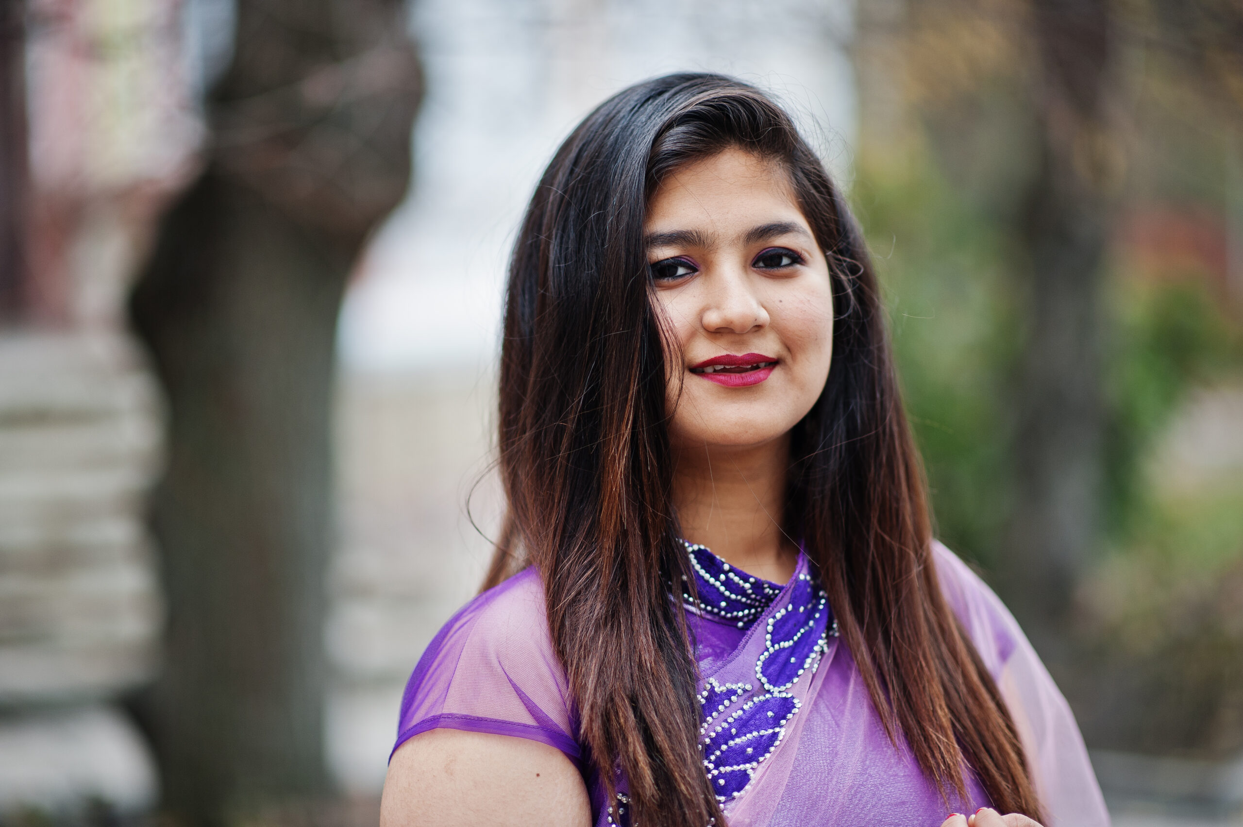 Close up portrait of indian hindu girl at traditional violet saree posed at street.